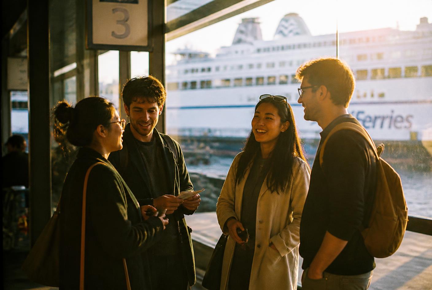 International team of young professionals talking at a ferry terminal at golden hour